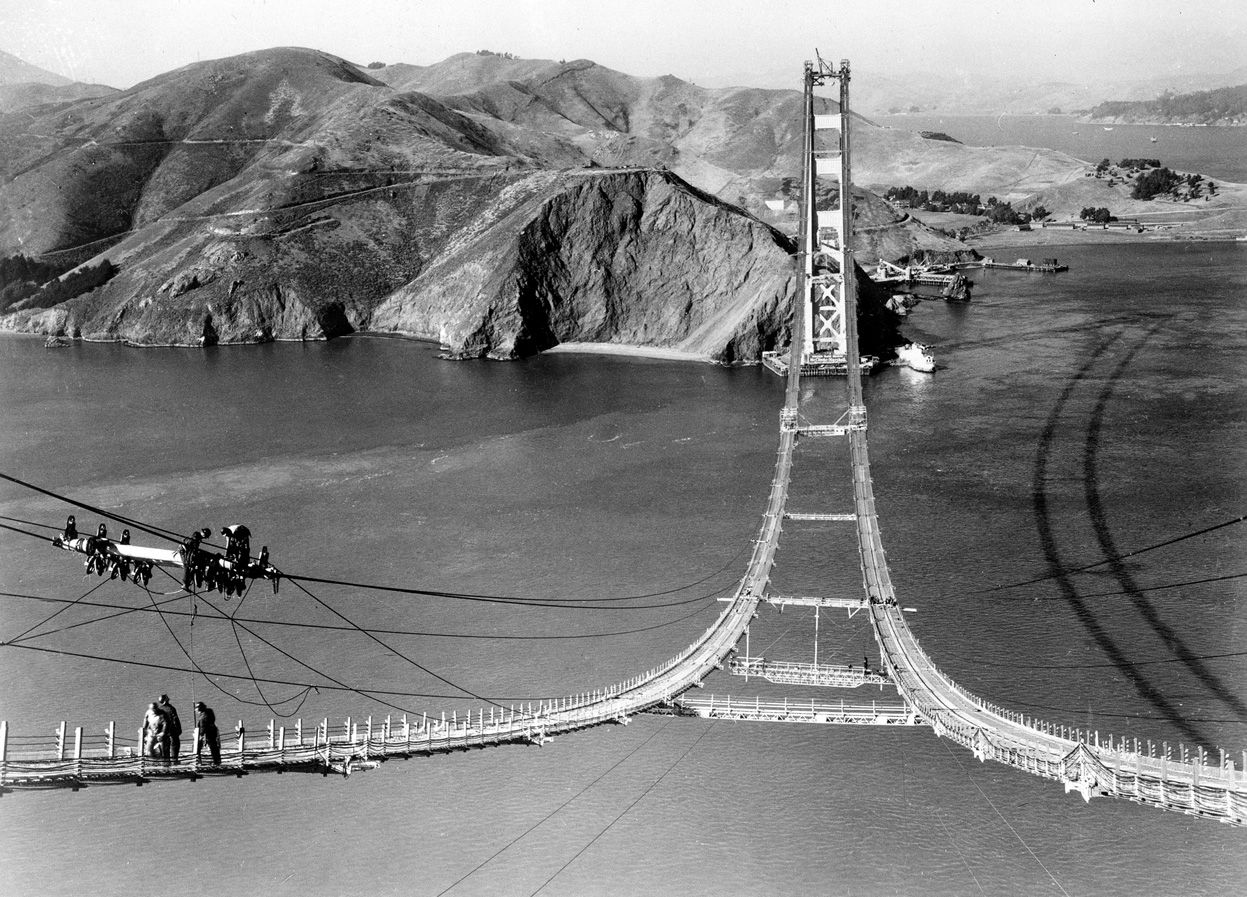 Workers complete the catwalks for the Golden Gate Bridge, hundreds of feet above the water, prior to spinning the bridge cables during construction in 1935